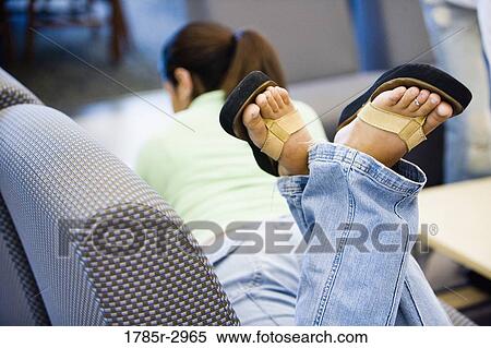 Stock Photography - Woman lying on the sofa with feet in the air. Fotosearch