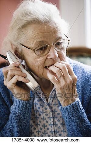Worried and pensive senior woman talking on cordless phone View Large Photo Image Stock Photo - Worried and pensive senior woman talking on cordless phone. Fotosearch