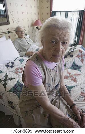 Worried senior woman sitting on bed with bedridden senior man View Large Photo Image Stock Photography - Worried senior woman sitting on bed with bedridden senior man. Fotosearch