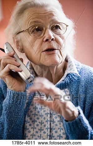 Worried senior woman talking on cordless phone View Large Photo Image Stock Image - Worried senior woman talking on cordless phone. Fotosearch