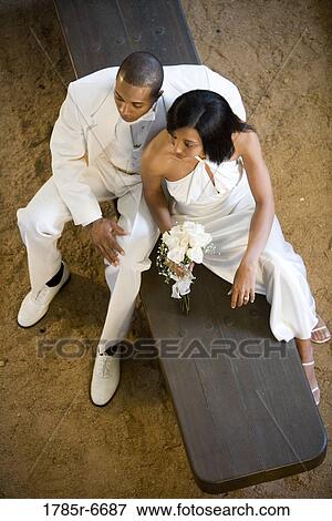 Young bride and groom seated on a bench View Large Photo Image Stock Photo - Young bride and groom seated on a bench. Fotosearch