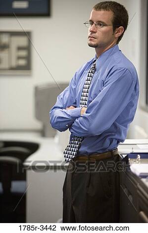 Young businessman standing in office View Large Photo Image Stock Image - Young businessman standing in office. Fotosearch