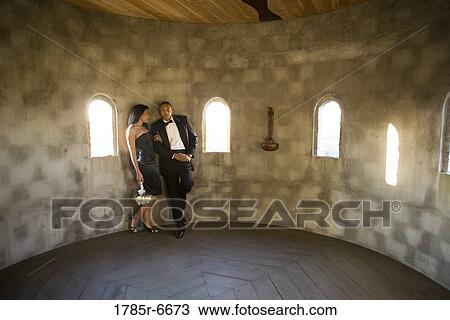 Stock Image - Young couple in formal attire leaning against wall in castle turret. Fotosearch