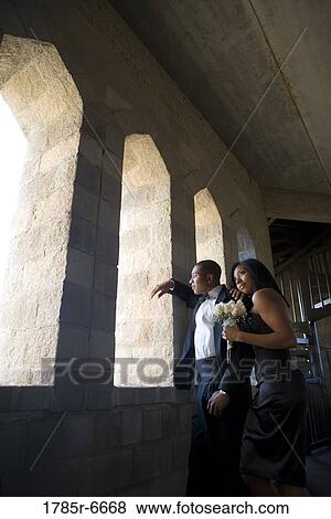 Stock Photo - Young couple in formal attire leaning against a large window inside a medieval castle. Fotosearch