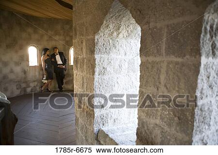 Stock Photography - Young couple in formal attire leaning against wall in castle turret. Fotosearch