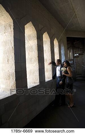 Stock Photo - Young couple in formal attire looking out window of medieval castle. Fotosearch