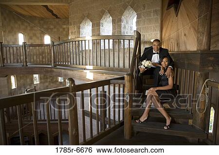 Stock Photograph - Young couple in formal attire sitting on stairs inside medieval castle. Fotosearch