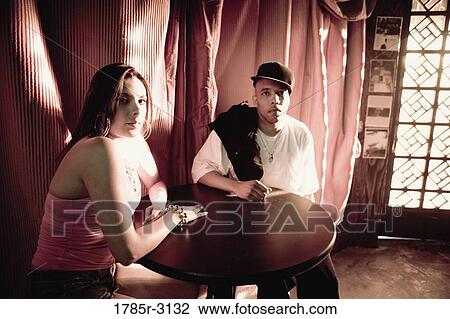 Young couple in hip-hop fashion sitting at a table View Large Photo Image Stock Image - Young couple in hip-hop fashion sitting at a table. Fotosearch