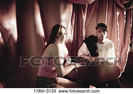 Young couple in hip-hop fashion sitting at a table View Large Photo Image Stock Image - Young couple in hip-hop fashion sitting at a table. Fotosearch