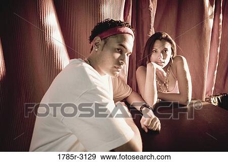 Young couple in hip-hop fashion sitting at a table View Large Photo Image Stock Photo - Young couple in hip-hop fashion sitting at a table. Fotosearch