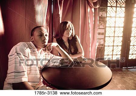 Young couple in hip-hop fashion sitting at a table View Large Photo Image Stock Photo - Young couple in hip-hop fashion sitting at a table. Fotosearch
