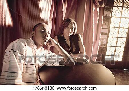 Stock Photograph - Young couple in hip-hop fashion sitting at a table. Fotosearch