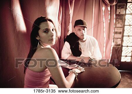 Young couple in hip-hop fashion sitting at a table View Large Photo Image Stock Photography - Young couple in hip-hop fashion sitting at a table. Fotosearch