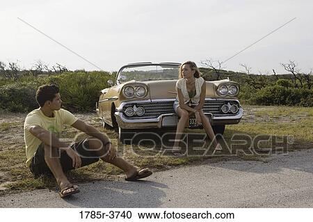 Young couple sitting beside antique convertible car View Large Photo Image Stock Image - Young couple sitting beside antique convertible car. Fotosearch