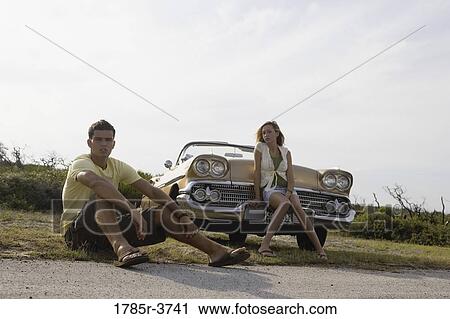 Young couple sitting beside antique convertible car View Large Photo Image Stock Image - Young couple sitting beside antique convertible car. Fotosearch