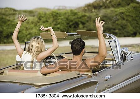 Young couple sitting in antique convertible car waving their arms View Large Photo Image Picture - Young couple sitting in antique convertible car waving their arms. Fotosearch