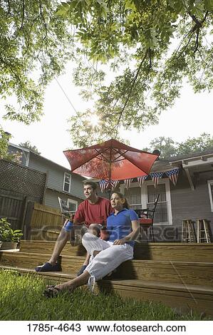 Young couple sitting on steps of their backyard patio with 4th of July decorations in background View Large Photo Image Stock Image - Young couple sitting on steps of their backyard patio with 4th of July decorations in background. Fotosearch
