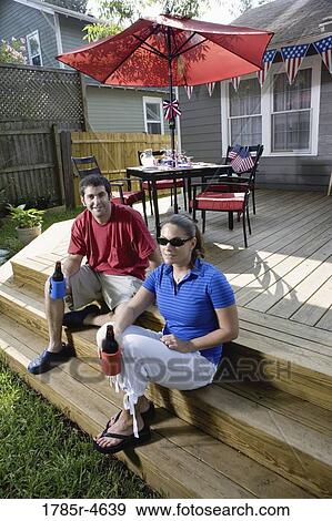 Young couple sitting on steps of their backyard patio with 4th of July decorations in background View Large Photo Image Stock Photo - Young couple sitting on steps of their backyard patio with 4th of July decorations in background. Fotosearch