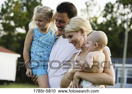 Stock Image - Young family standing outside. Fotosearch