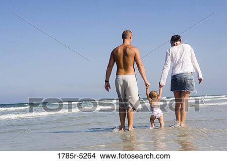 Picture - Young family strolling along the beach. Fotosearch