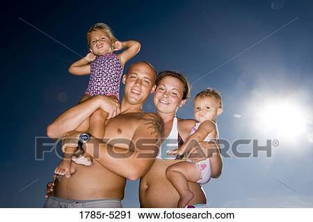 Young family with two daughters in swimsuits against a clear blue sky View Large Photo Image Stock Image - Young family with two daughters in swimsuits against a clear blue sky. Fotosearch
