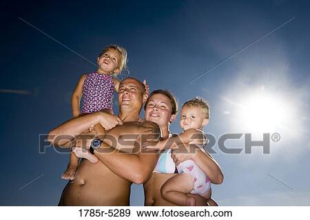 Young family with two daughters in swimsuits against a clear blue sky View Large Photo Image Stock Photo - Young family with two daughters in swimsuits against a clear blue sky. Fotosearch