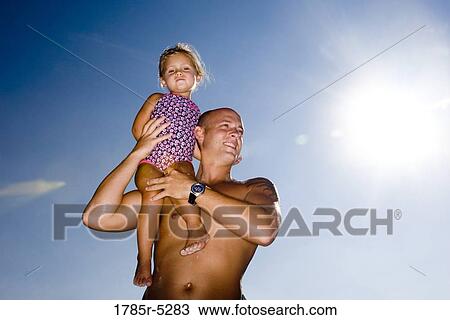 Young father holding daughter up on his shoulder View Large Photo Image Stock Image - Young father holding daughter up on his shoulder. Fotosearch