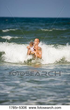 Young father playing with young daughter in the ocean View Large Photo Image Stock Photograph - Young father playing with young daughter in the ocean. Fotosearch