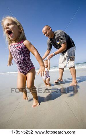 Young father with daughters on the beach View Large Photo Image Stock Image - Young father with daughters on the beach. Fotosearch