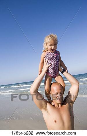 Young girl at the beach standing on father's shoulders View Large Photo Image Stock Image - Young girl at the beach standing on father's shoulders. Fotosearch