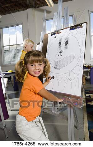 Young girl drawing on easels in art class View Large Photo Image Stock Photo - Young girl drawing on easels in art class. Fotosearch