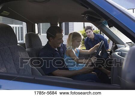 Young girl sitting on father's lap in pickup truck, pretending to drive View Large Photo Image Picture - Young girl sitting on father's lap in pickup truck, pretending to drive. Fotosearch