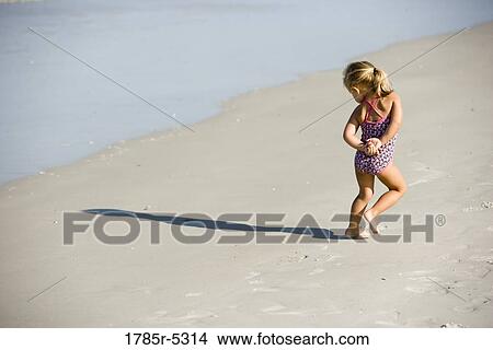 Young girl walking on beach, watching the waves View Large Photo Image Picture - Young girl walking on beach, watching the waves. Fotosearch