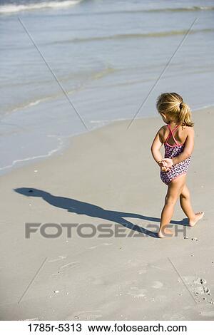 Young girl walking on beach, watching the waves View Large Photo Image Stock Image - Young girl walking on beach, watching the waves. Fotosearch