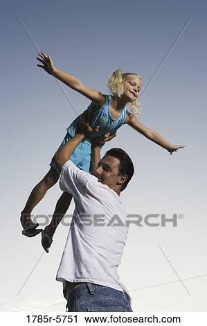 Young girl with arms outstretched, lifted by her father View Large Photo Image Stock Image - Young girl with arms outstretched, lifted by her father. Fotosearch