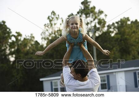 Young girl with arms outstretched, lifted by her father View Large Photo Image Stock Photo - Young girl with arms outstretched, lifted by her father. Fotosearch