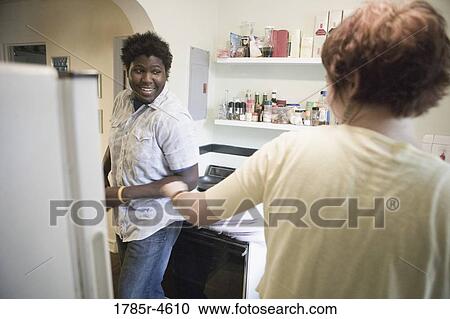 Young inter-racial couple conversing in a kitchen View Large Photo Image Stock Image - Young inter-racial couple conversing in a kitchen. Fotosearch