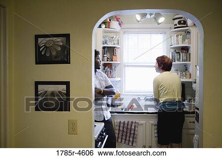 Young inter-racial couple conversing in a kitchen View Large Photo Image Stock Photograph - Young inter-racial couple conversing in a kitchen. Fotosearch