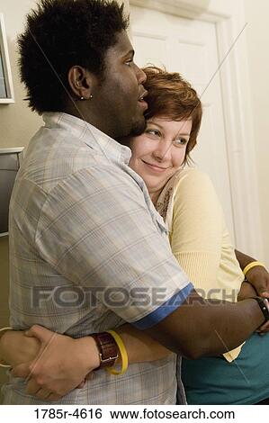 Stock Photograph - Young inter-racial couple embracing each other. Fotosearch