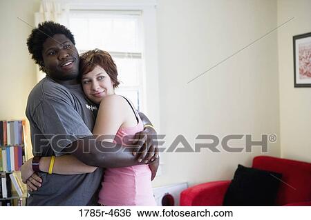 Stock Photograph - Young inter-racial couple embracing each other. Fotosearch