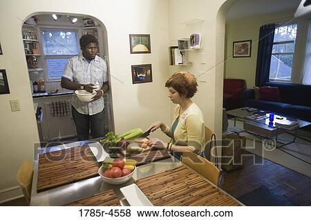 Stock Photo - Young inter-racial couple preparing food together. Fotosearch