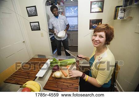 Young inter-racial couple preparing food together View Large Photo Image Stock Photo - Young inter-racial couple preparing food together. Fotosearch