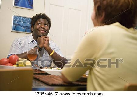 Young inter-racial couple sitting at a dining table View Large Photo Image Stock Photo - Young inter-racial couple sitting at a dining table. Fotosearch