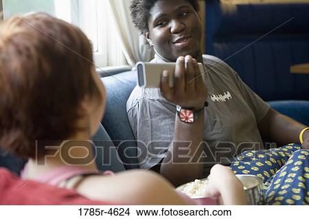 Picture - Young inter-racial couple sitting on a sofa. Fotosearch