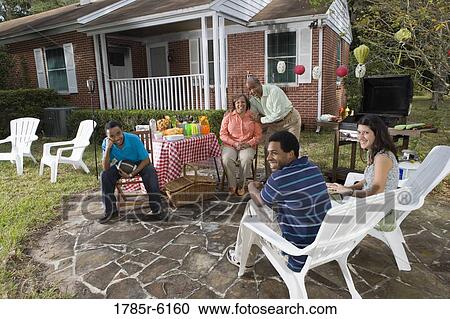 Stock Image - Young interracial couple enjoying backyard bbq with family. Fotosearch