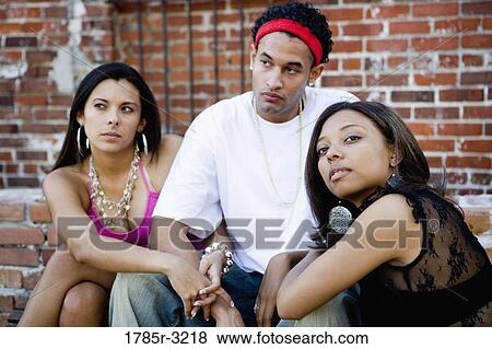 Young man and women in hip-hop fashion hanging out in a back alley View Large Photo Image Stock Photo - Young man and women in hip-hop fashion hanging out in a back alley. Fotosearch