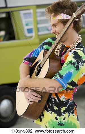 Young man in hippie fashion holding guitar View Large Photo Image Stock Image - Young man in hippie fashion holding guitar. Fotosearch