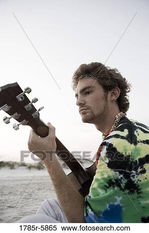 Young man in hippie fashion playing guitar at beach View Large Photo Image Stock Photography - Young man in hippie fashion playing guitar at beach. Fotosearch