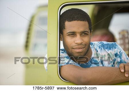 Young man leaning on vehicle window View Large Photo Image Stock Photo - Young man leaning on vehicle window. Fotosearch