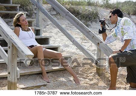 Young man photographing a young woman at the beach View Large Photo Image Stock Photo - Young man photographing a young woman at the beach. Fotosearch
